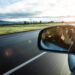 photographing from car window. Reflection in car mirror of hands with camera.